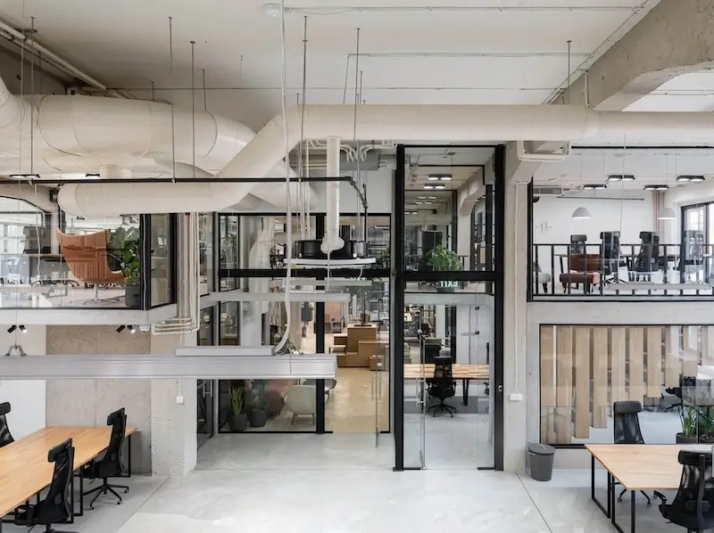 Lightbloom's office inside Puzl CoWorking in Budapest, with people working at long desks under a glazed mezzanine.